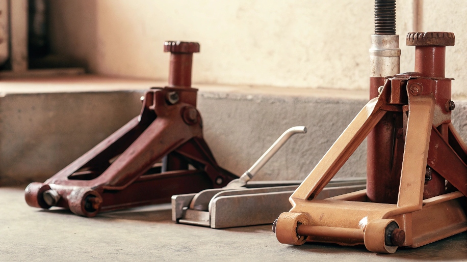 A close-up of a jack handle's notched end being inserted into the release valve.